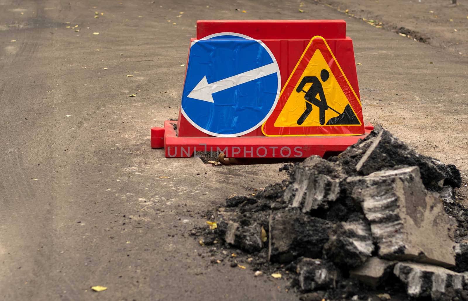road sign, detour, road repair on the background of the road and broken asphalt pieces, close up