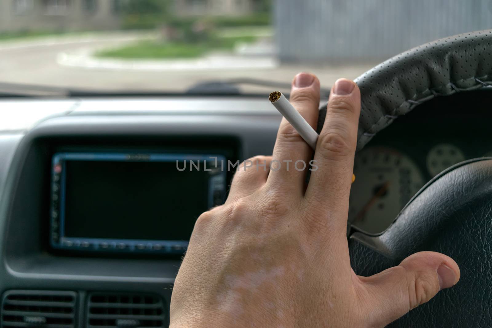 the hand of the driver of the car with skin disease "vitiligo" holds a cigarette by jk3030