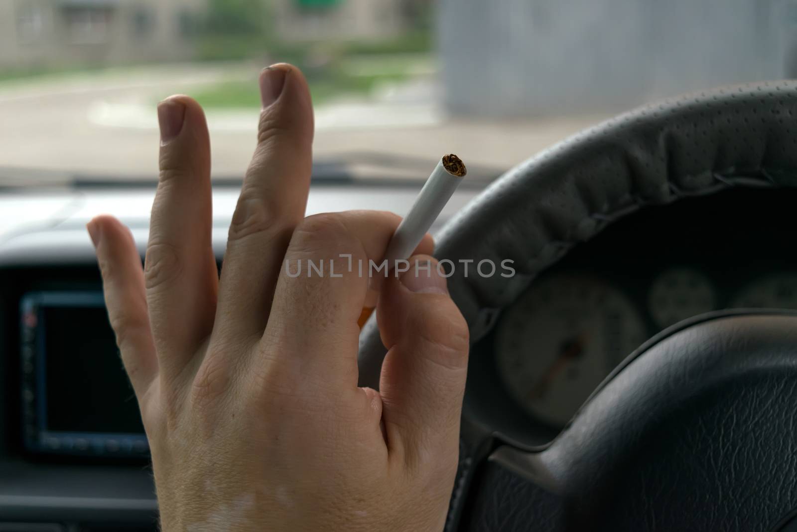 close-up, the hand of the driver of the car holds a cigarette