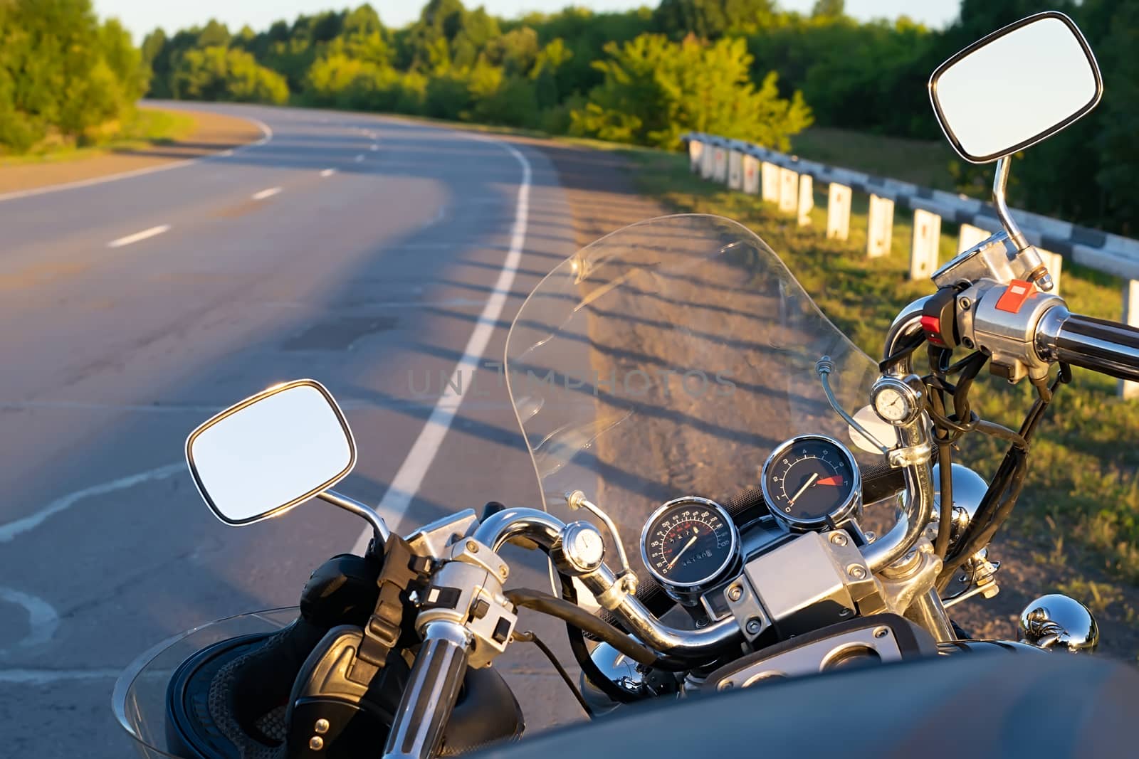 view of the steering wheel of an old vintage powerful motorcycle from the position of a motorcyclist against the background of the highway going around the bend