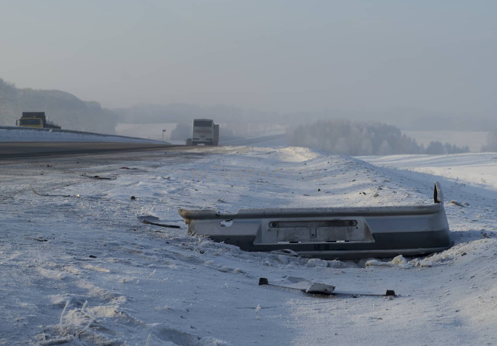 broken car bumper on the winter road by jk3030