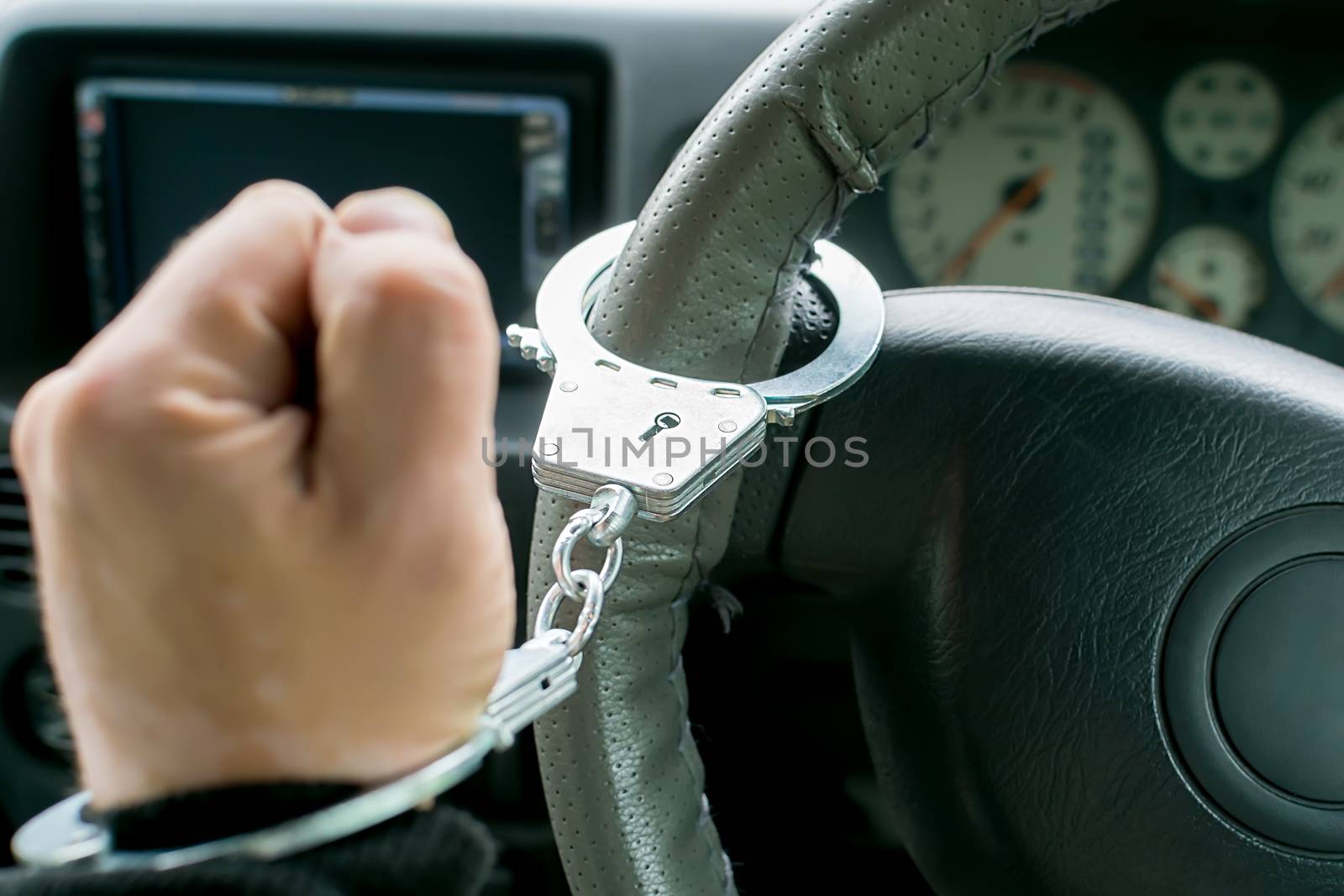 hand of the driver of the car, clenched into a fist, handcuffed to the steering wheel, arrest, prohibition of driving by a traffic violator