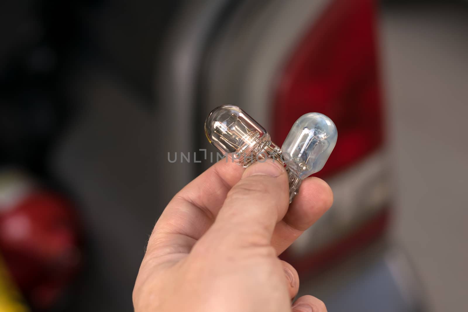 new and burnt out car light bulb, in man's hand