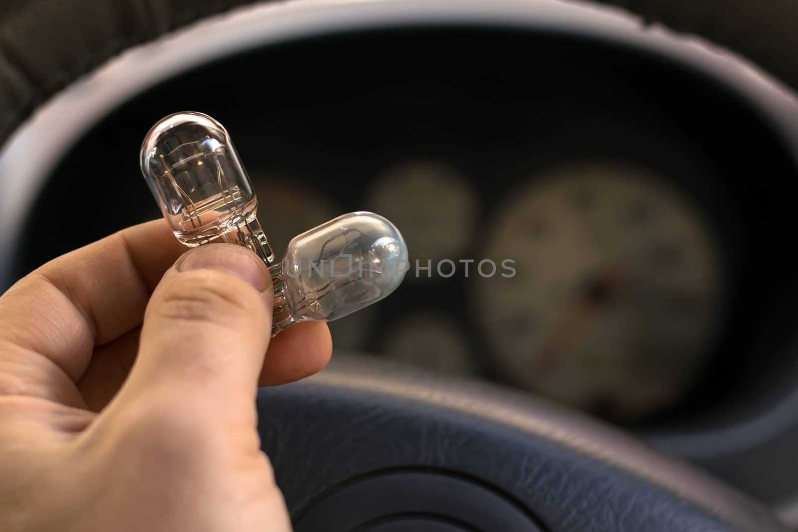 new and burnt out car light bulb, in man's hand by jk3030