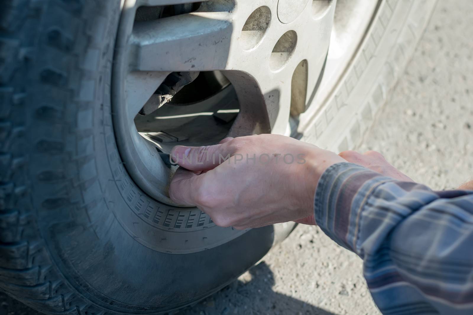 human hands insert the hose of the car pump to pump air into the wheel of the car