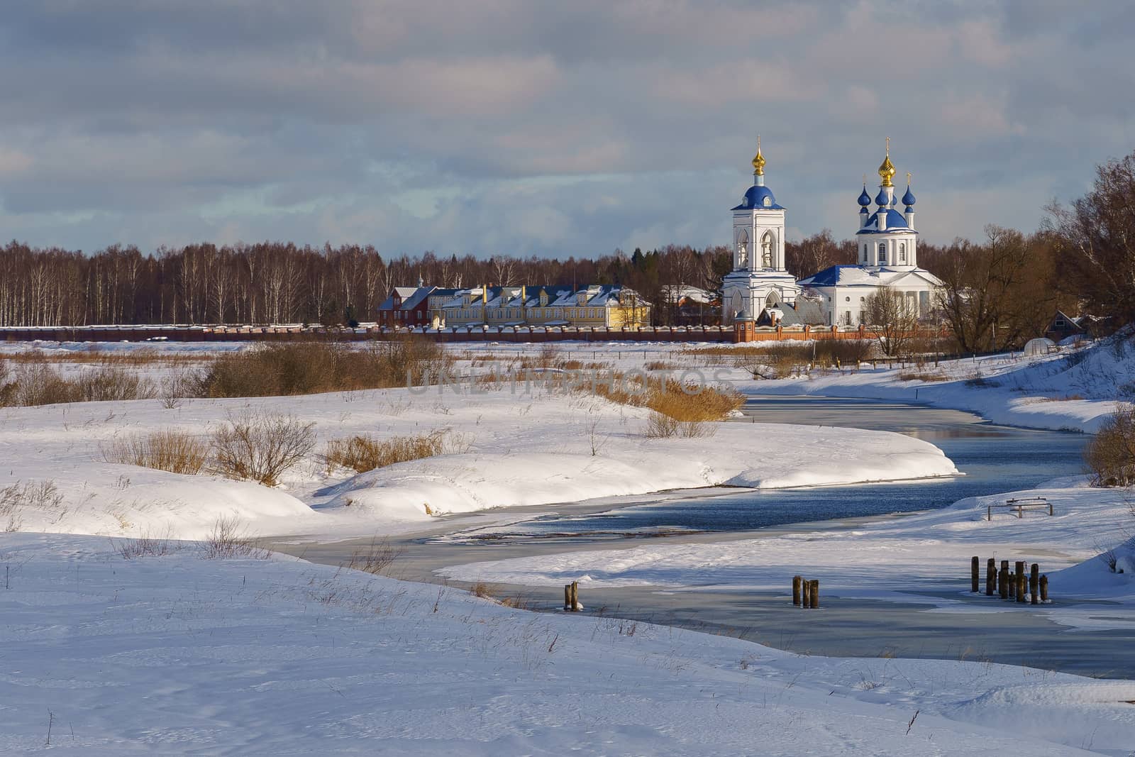 church in a snowy field on a river bank on a winter day by VADIM