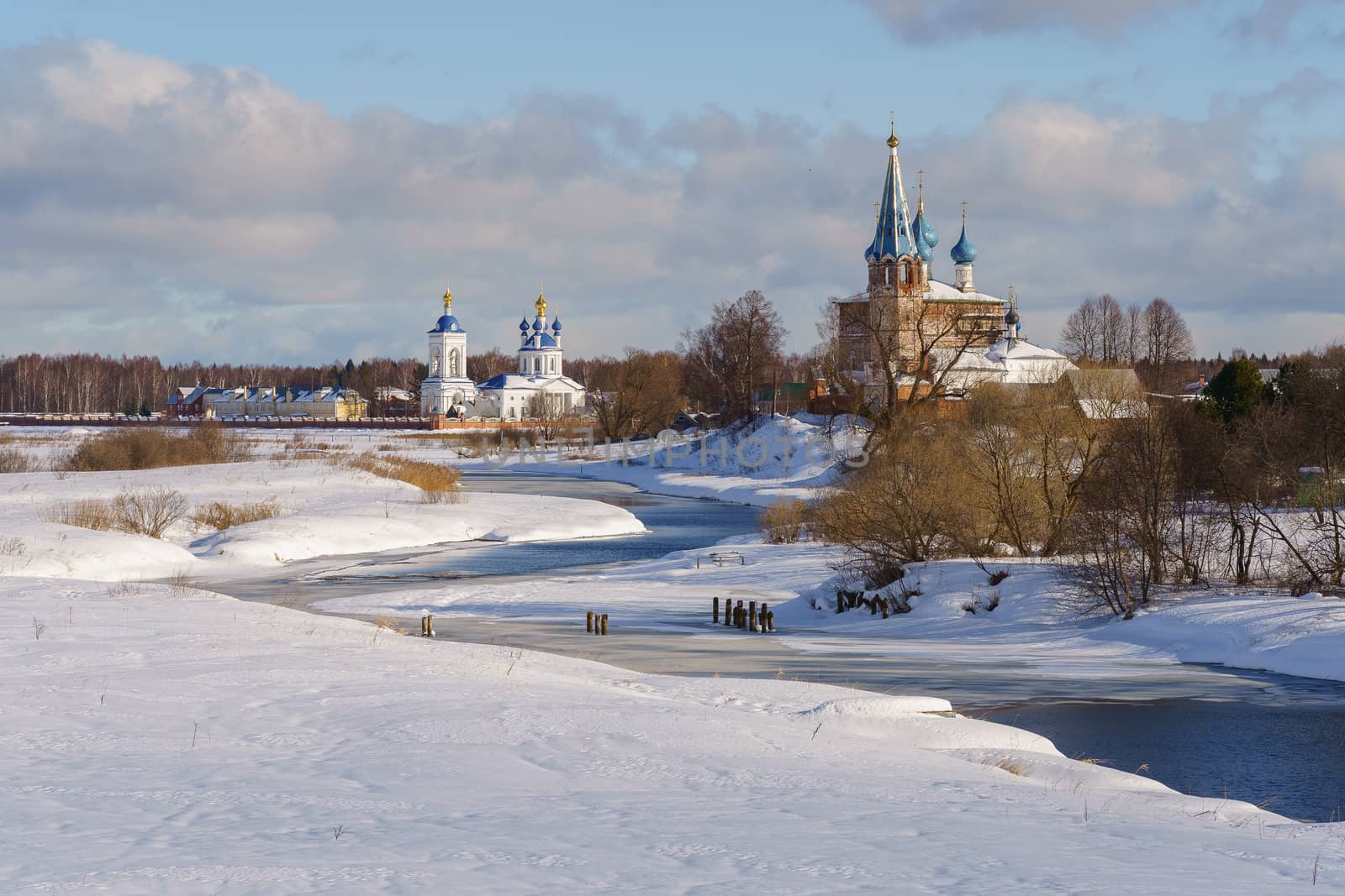 church in a snowy field on a river bank on a clear winter day