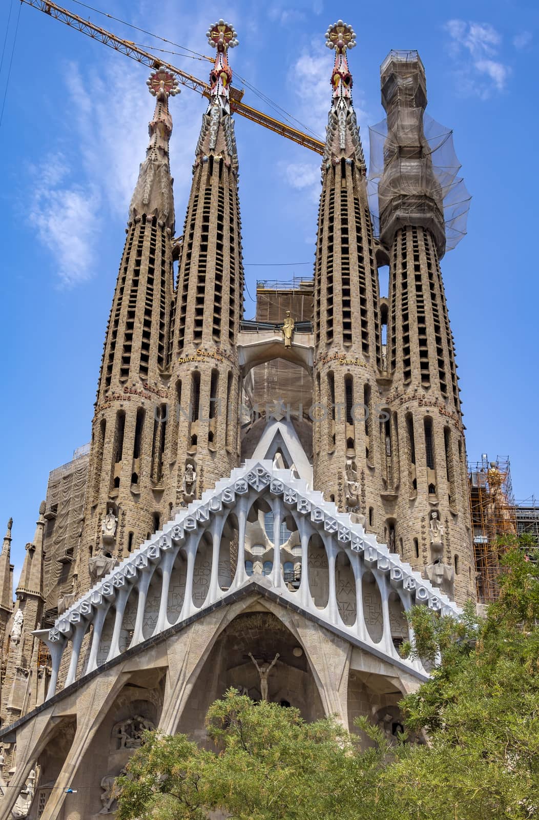 BARCELONA, SPAIN - JULY 5, 2016: La Sagrada Familia - the impressive cathedral designed by Gaudi, which is being build since 19 March 1882 and is not finished yet.

Barcelona, Spain - July 5, 2016: La Sagrada Familia - the impressive cathedral designed by Gaudi, which is being build since 19 March 1882 and is not finished yet. People are walking by park.