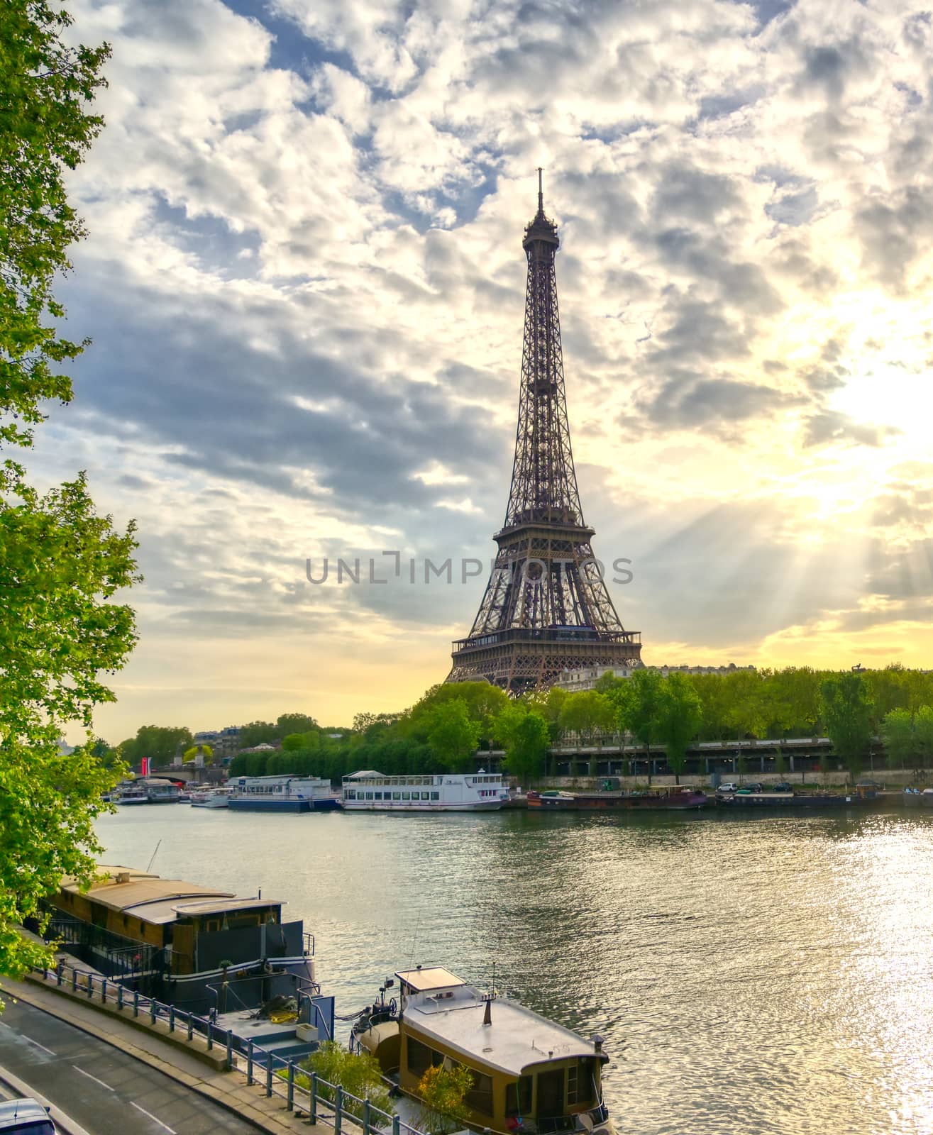 The Eiffel Tower across the Seine River in Paris, France on a sunny day with beautiful clouds.