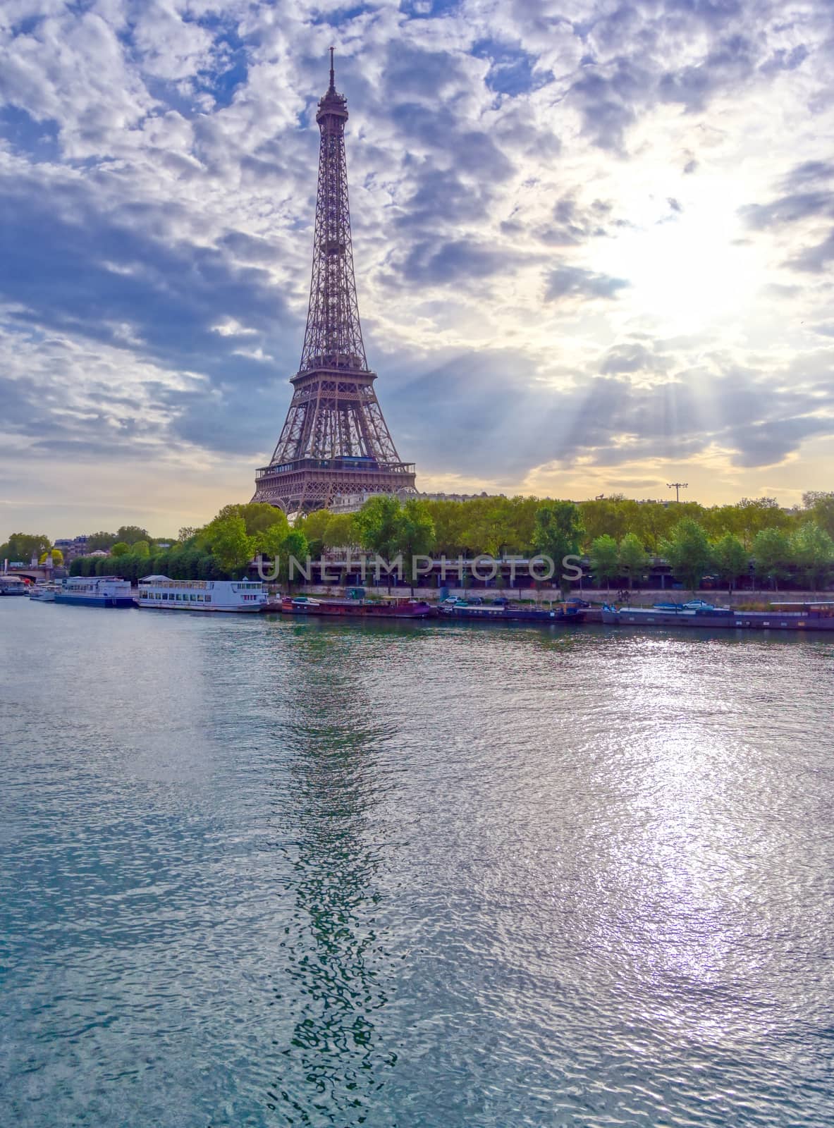 The Eiffel Tower across the Seine River in Paris, France on a sunny day with beautiful clouds.