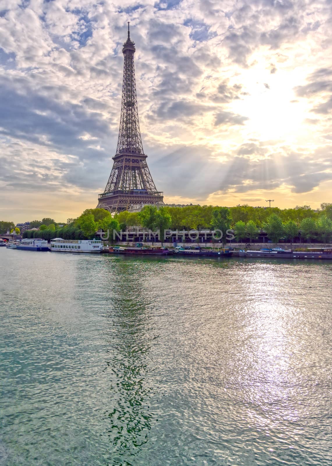 The Eiffel Tower across the Seine River in Paris, France on a sunny day with beautiful clouds.