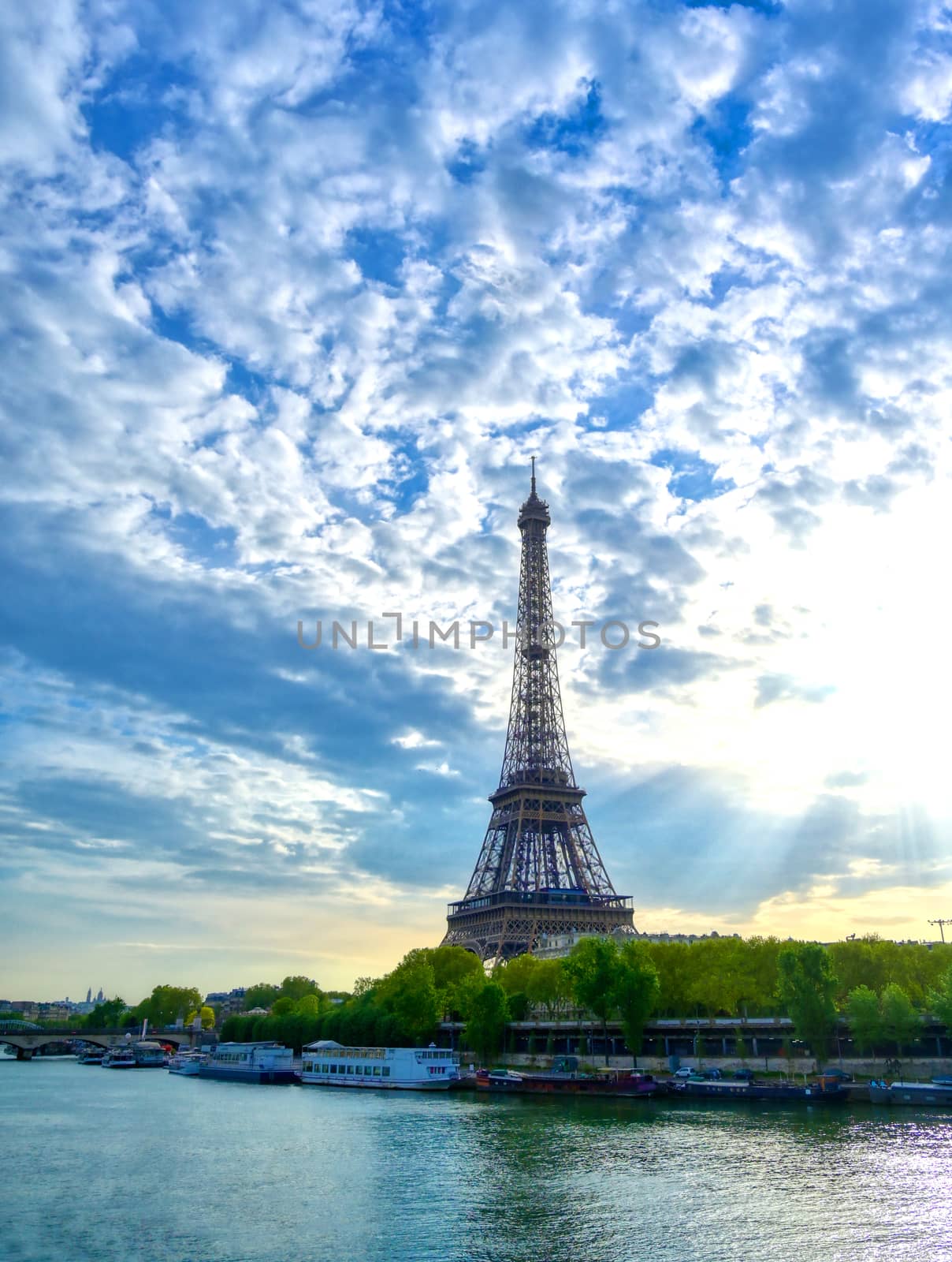 The Eiffel Tower across the Seine River in Paris, France on a sunny day with beautiful clouds.