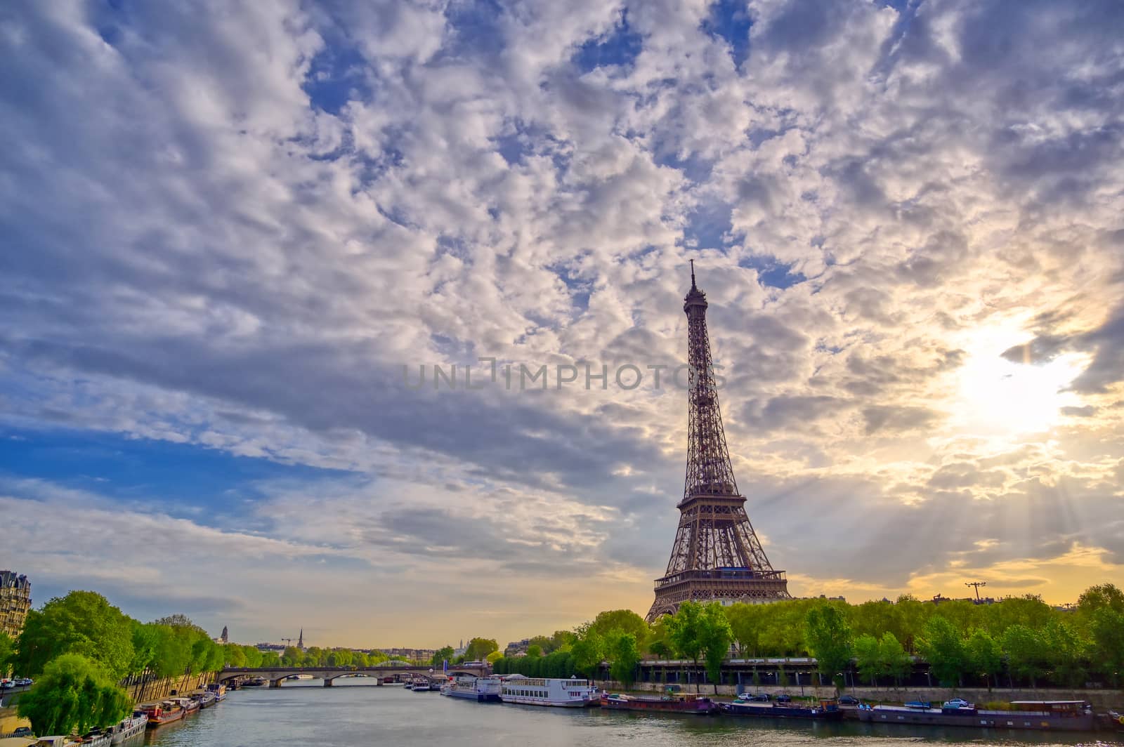 The Eiffel Tower across the Seine River in Paris, France on a sunny day with beautiful clouds.