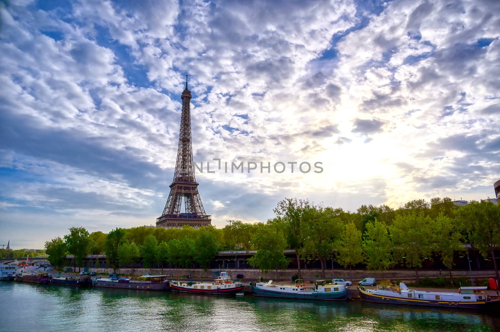 The Eiffel Tower across the Seine River in Paris, France on a sunny day with beautiful clouds.