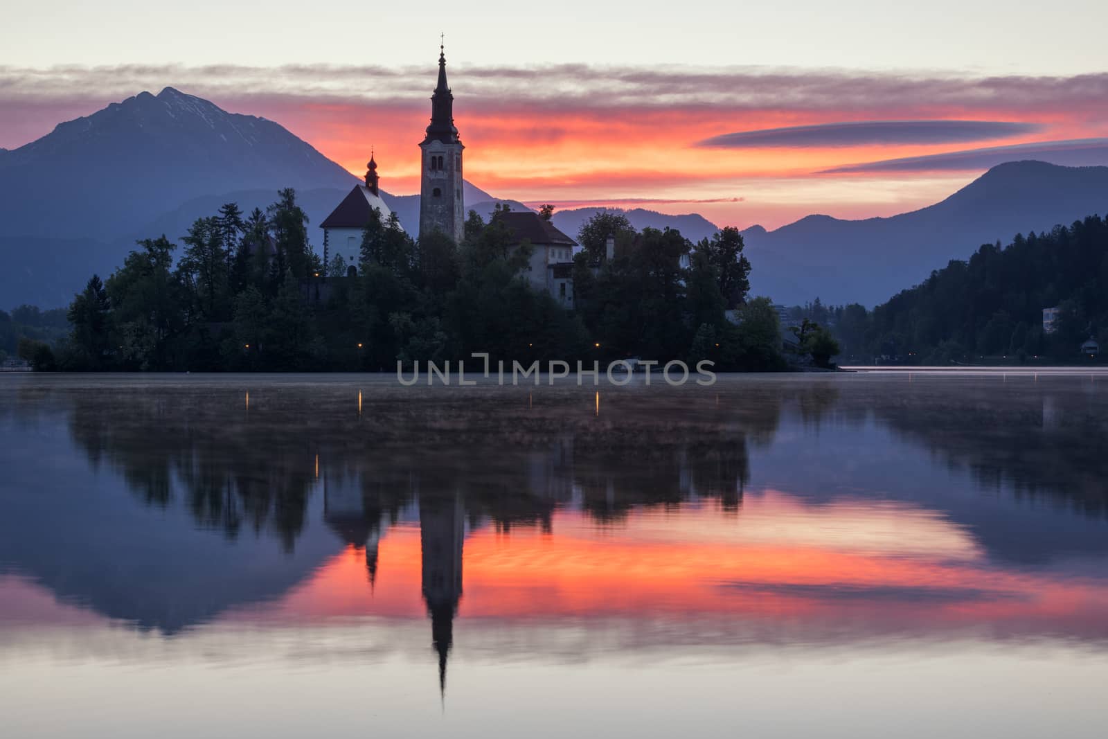 Dramatic sunrise on lake Bled, sunrise view on Bled lake, island, Pilgrimage Church of the Assumption of Maria and Castle with mountain range (Stol, Vrtaca, Begunjscica). Bled, Slovenia,