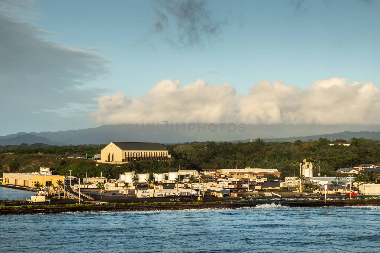 Nawiliwili, Kauai, Hawaii, USA. - January 16, 2020: Early morning light on Matson container yard in port with large self-storage buidling on hill top under light blue cloudscape.