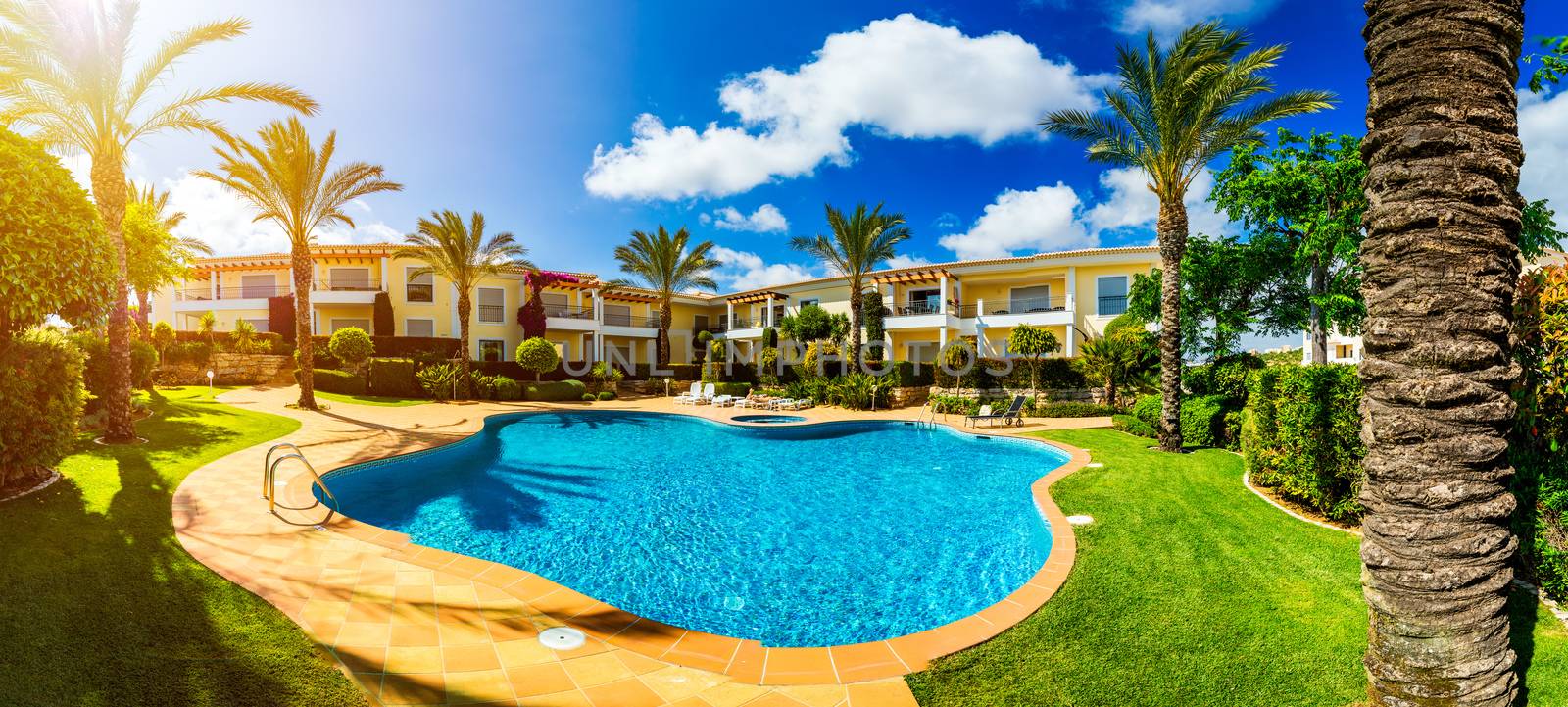 Great backyard with swimming pool, hot tub and lounge chairs. Swimming pool in backyard. Incredible swimming pool and garden with palm trees and flowers in a sunny day.