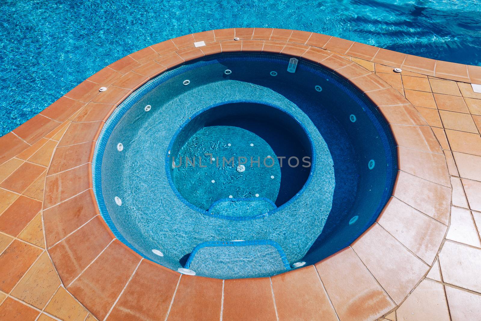 Swimming pool, sun-loungers and palm trees during a warm sunny day, paradise destination for vacations. Backyard swimming pool with garden full of palm trees and flowers. Backyard with swimming pool.