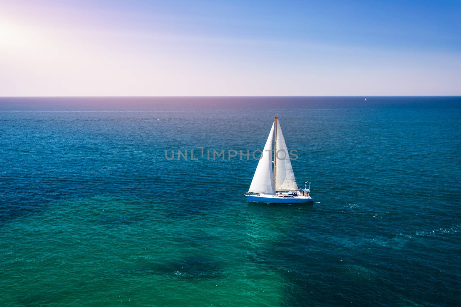 White sail boat isolated in blue sea water. Sailboat in the sea in the sunlight, luxury summer adventure, active vacation in Mediterranean sea. Yacht sailing on opened sea. Sailing boat. 