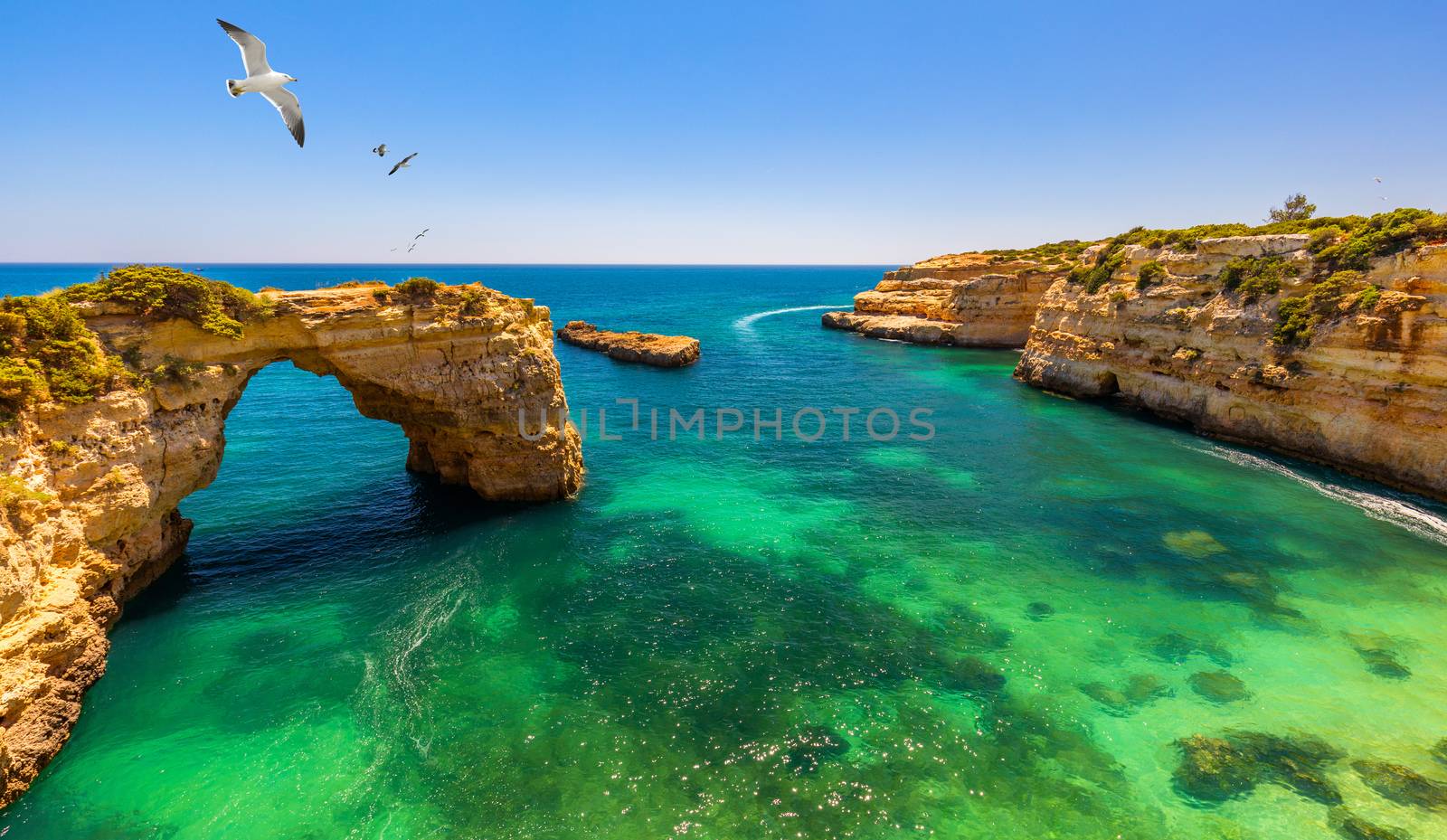 Natural arch above ocean, Arco de Albandeira, Algarve, Portugal. Stone arch at Praia de Albandeira, Lagoa, Algarve, Portugal. View of the natural arch Arco da Albandeira in the Algarve, Portugal. 