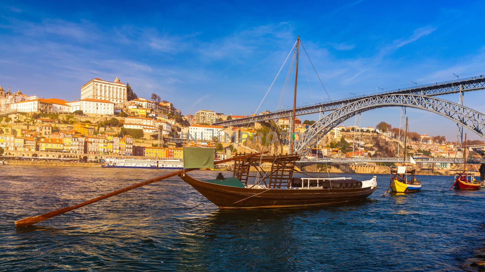 Port wine boats at the waterfront with Dom Luis bridge and the old town on the Douro River in Ribeira in the city centre of Porto in Porugal in Europe. Portugal, Porto