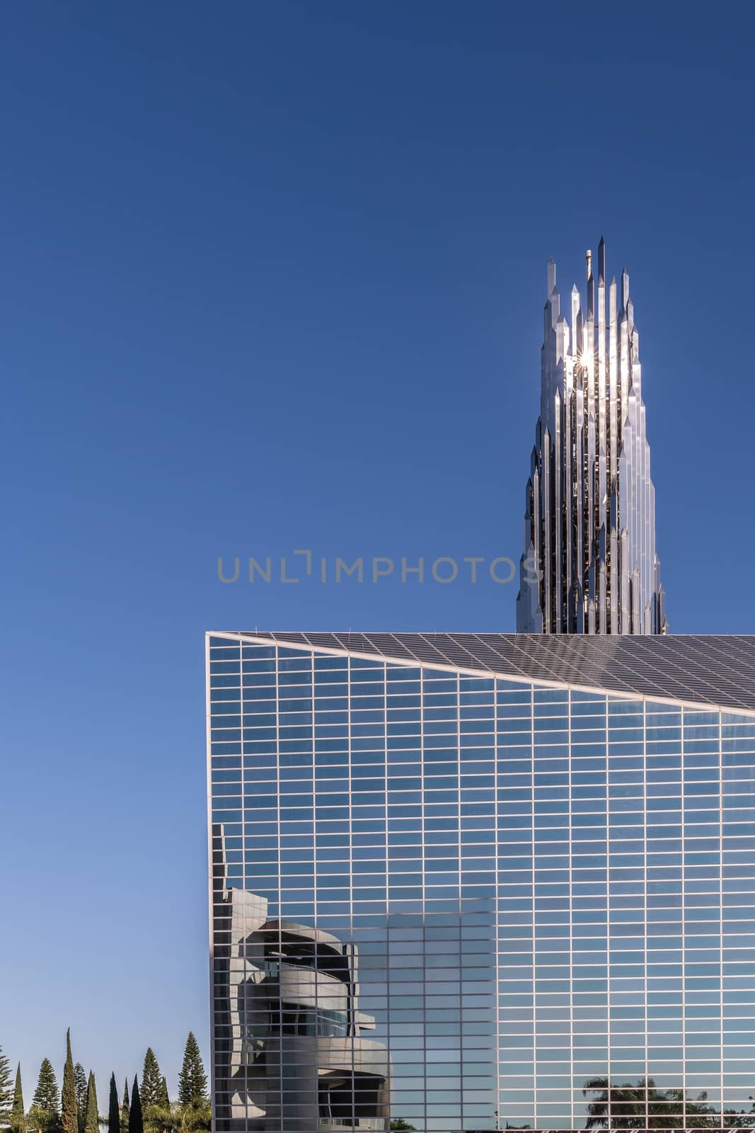 Garden Grove, California, USA - December 13, 2018: Crystal Christ Cathedral. Closeup of Church building and Crean Tower against blue sky. Cultural Center reflected in wall.