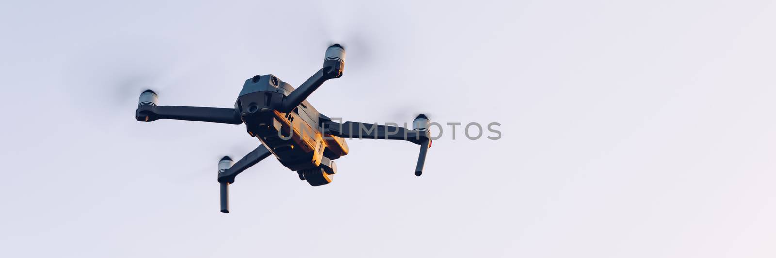 Drone flying over landscape. UAV drone copter flying with digital camera. Drone flying overhead in cloudy blue sky. Quad copter is flying over the  field.