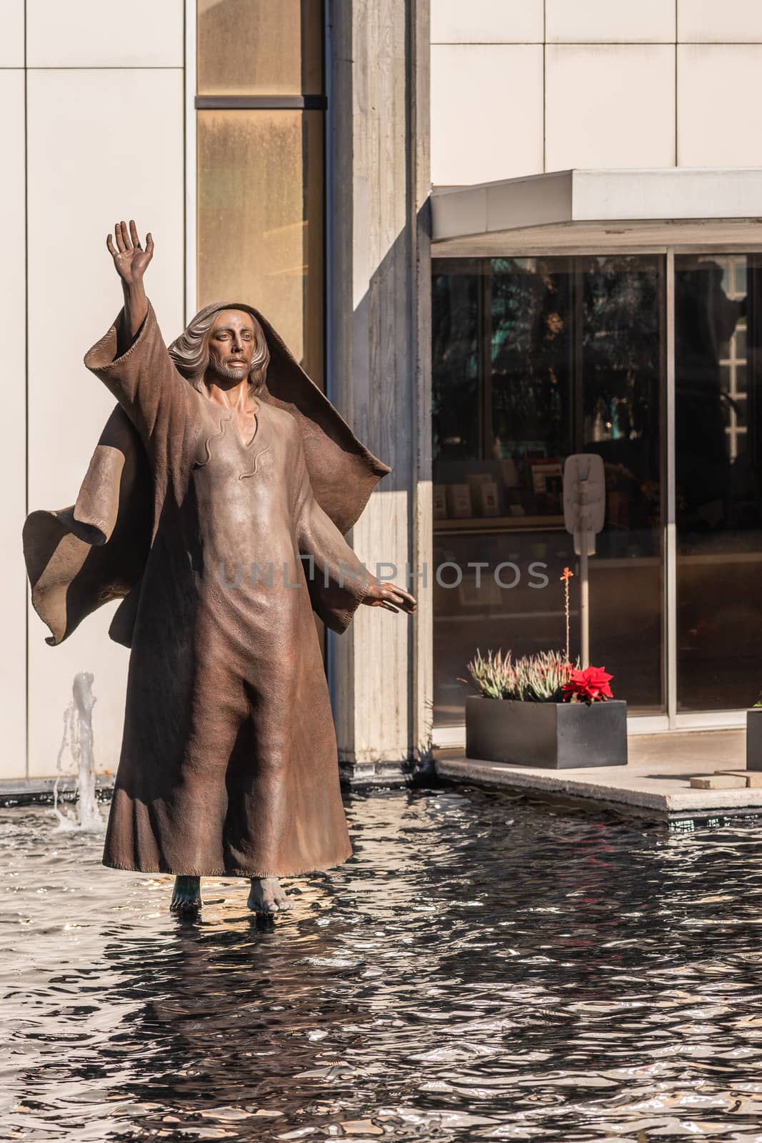 Garden Grove, California, USA - December 13, 2018: Crystal Christ Cathedral. Closeup of bronze statue of Jesus walking on water near Tower of Hope.