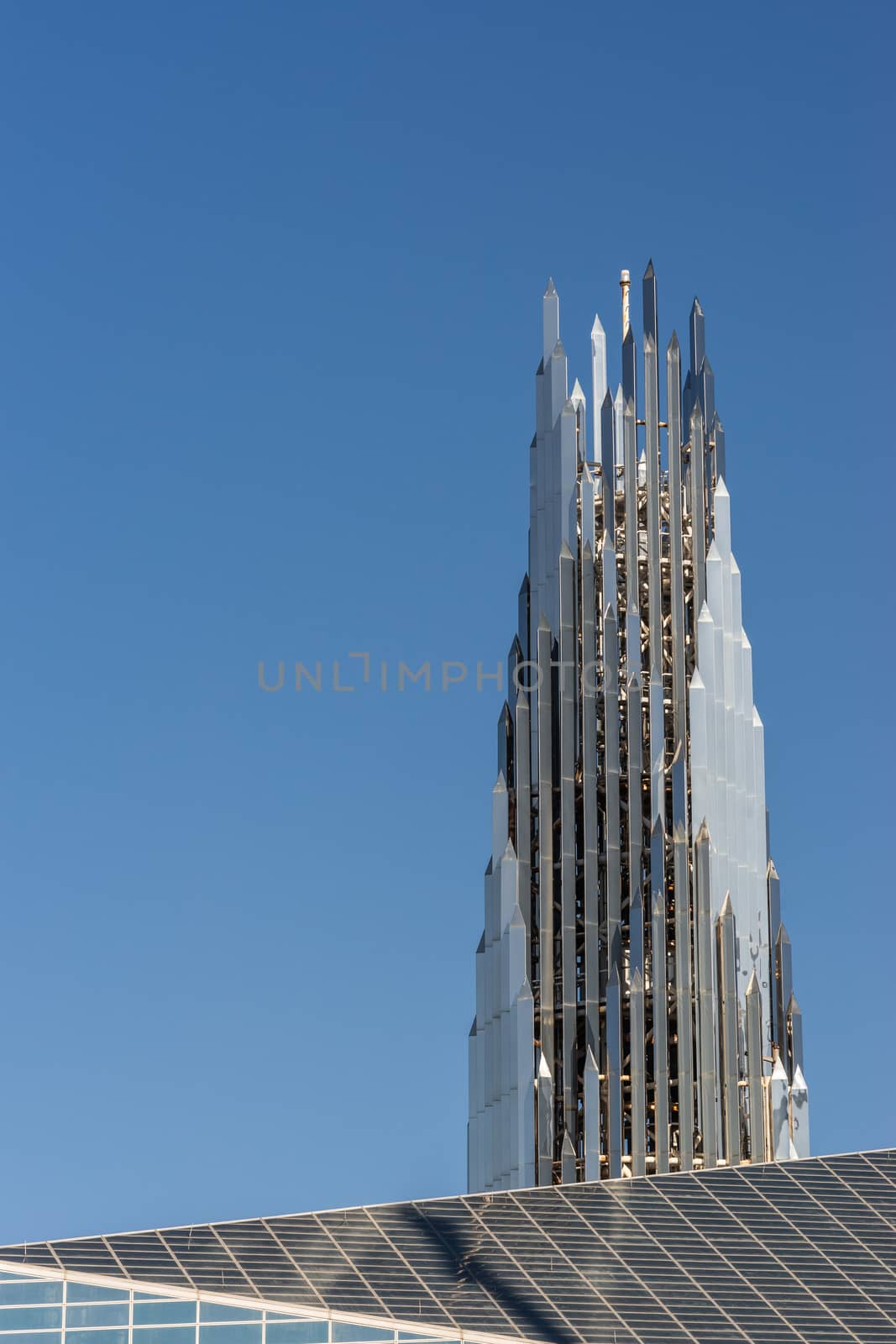 Garden Grove, California, USA - December 13, 2018: Crystal Christ Cathedral. Closeup of Crean Tower against blue sky. Roof of cathedral proper in front.