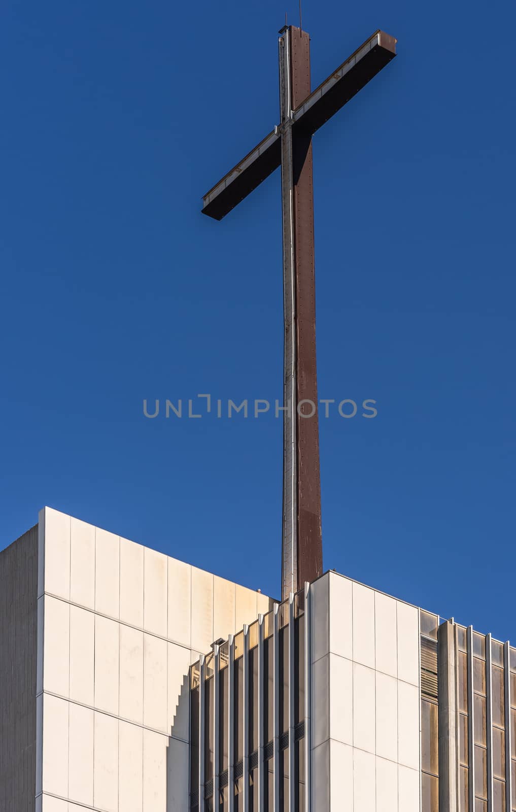 Garden Grove, California, USA - December 13, 2018: Crystal Christ Cathedral. Closeup of cross on top of tower of Hope against blue sky, White stone as base.