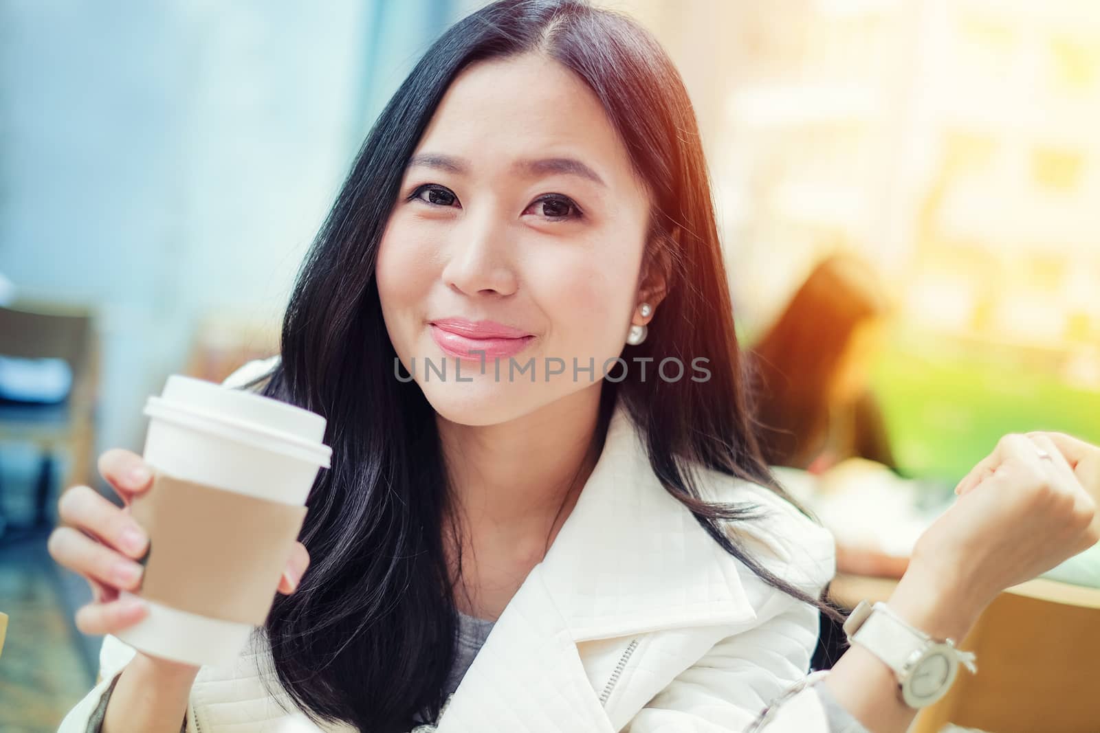 Woman drinking coffee at restaurant with sunrise streaming by Surasak