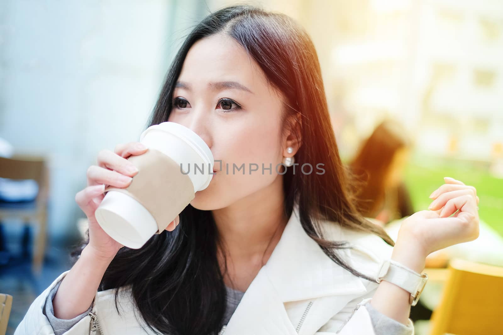 Woman drinking coffee at restaurant with sunrise streaming by Surasak