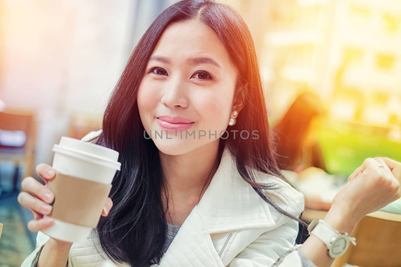 Woman drinking coffee at restaurant with sunrise streaming by Surasak