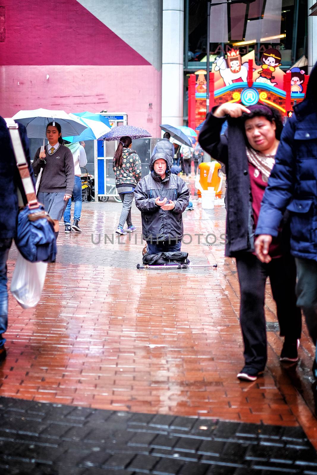 Hong Kong January 15 2016 : People passing a homeless man praying on the street on the rainy day in Hong Kong city in 15 Jan 2016