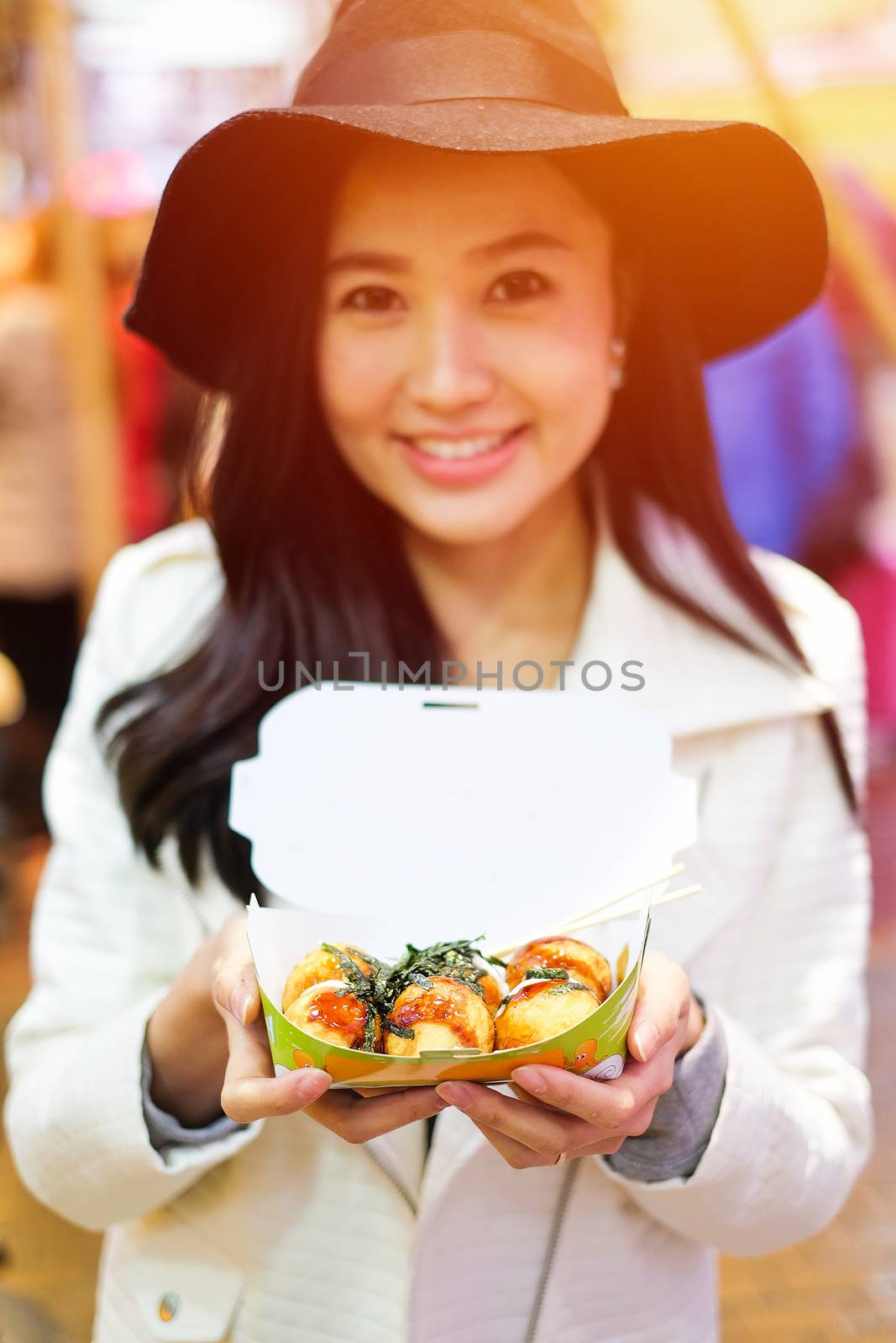 Chinese Asian young female model eating dumpling batter (Takoyaki) on Street in Hong Kong