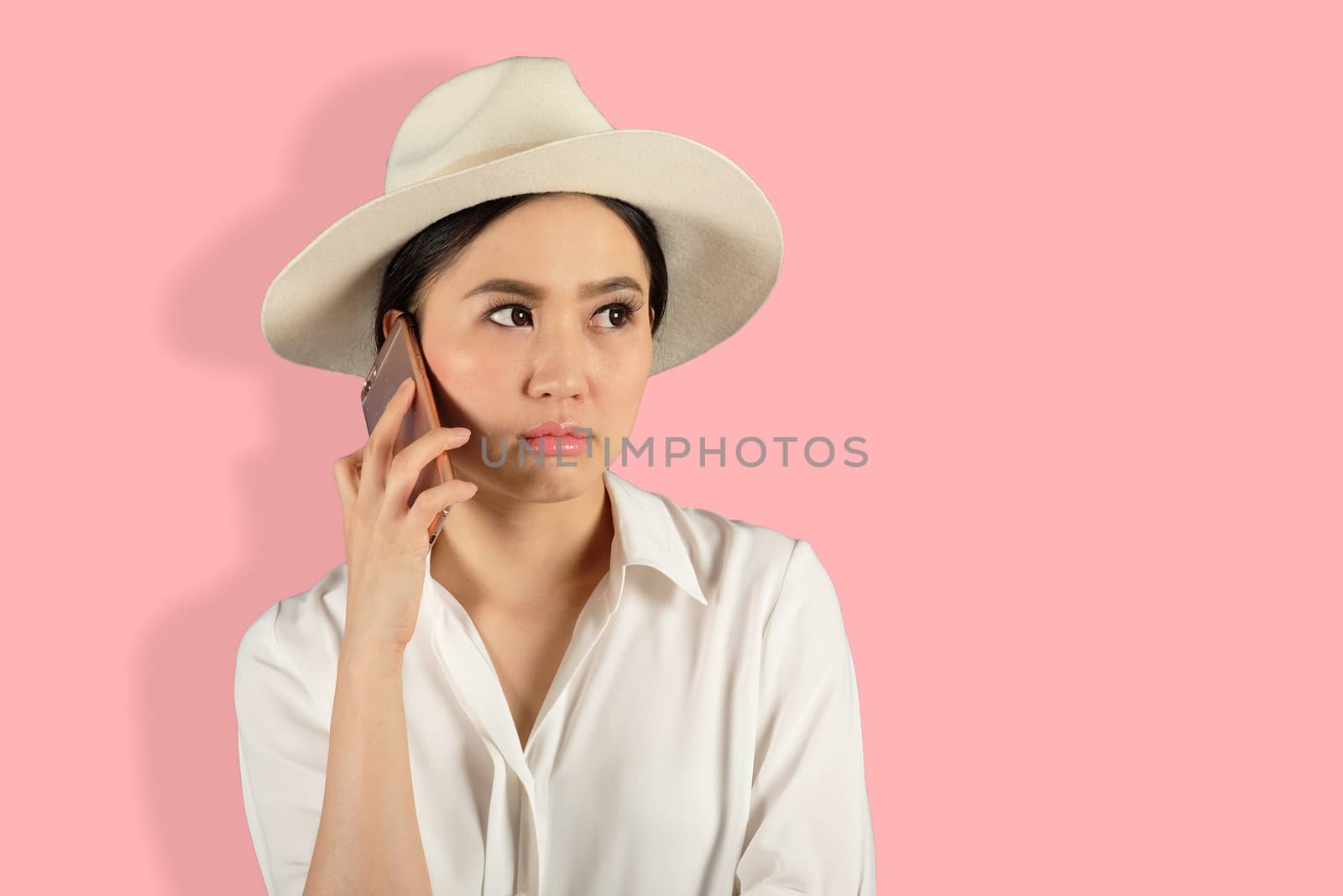 young attractive asian woman waiting answer for a smart phone on Pink backgroud 