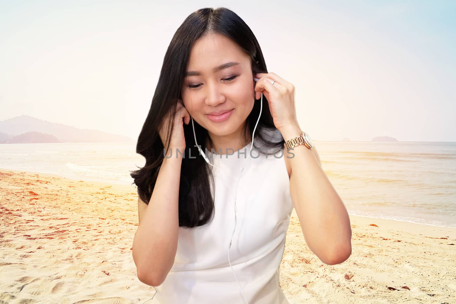 Young woman listening to music on Beach background by Surasak