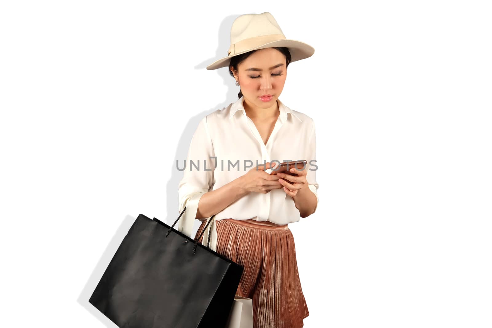 Young asian woman to see a smartphone and hold shopping bag by Surasak