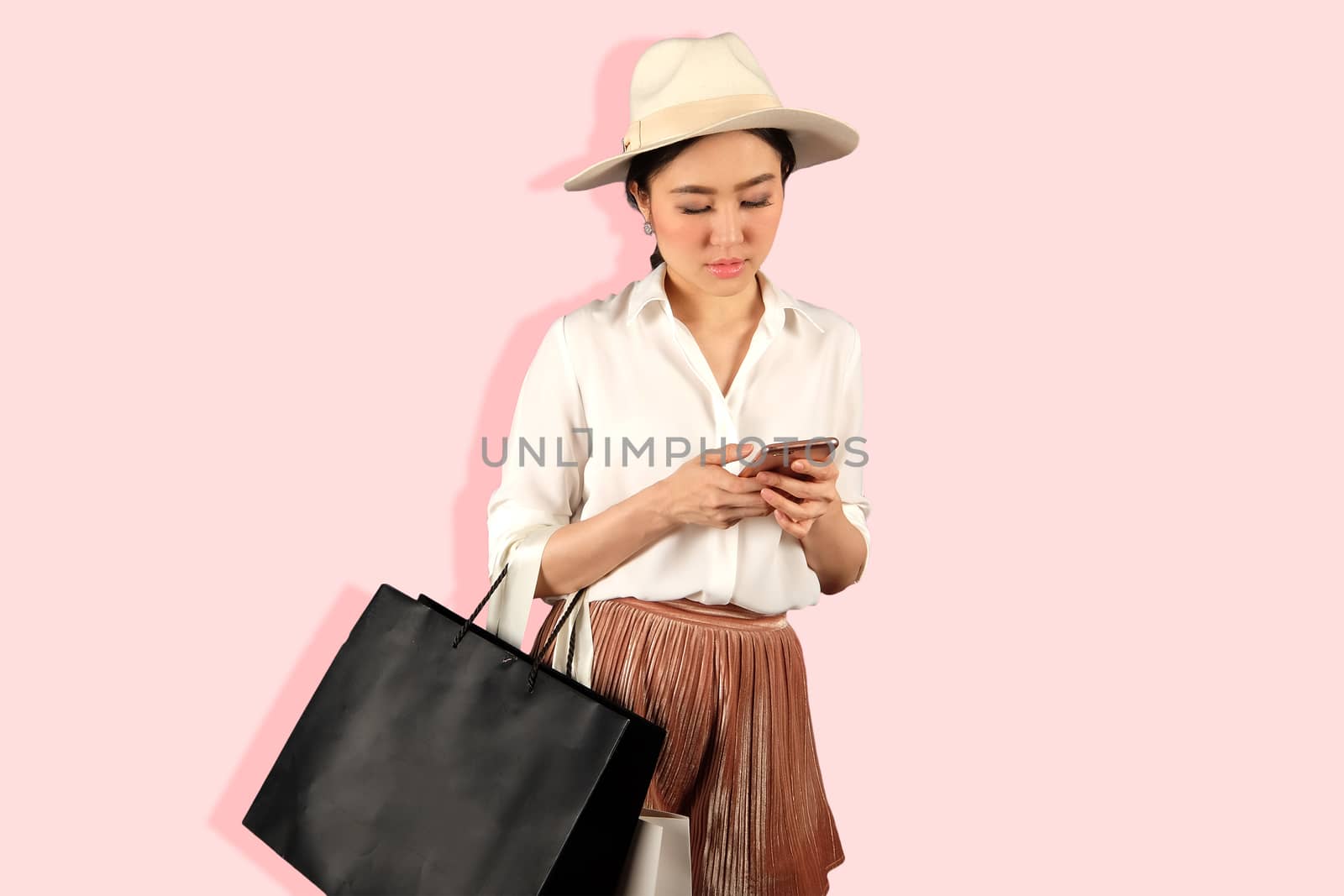 Young asian woman to see a smartphone and hold shopping bag by Surasak