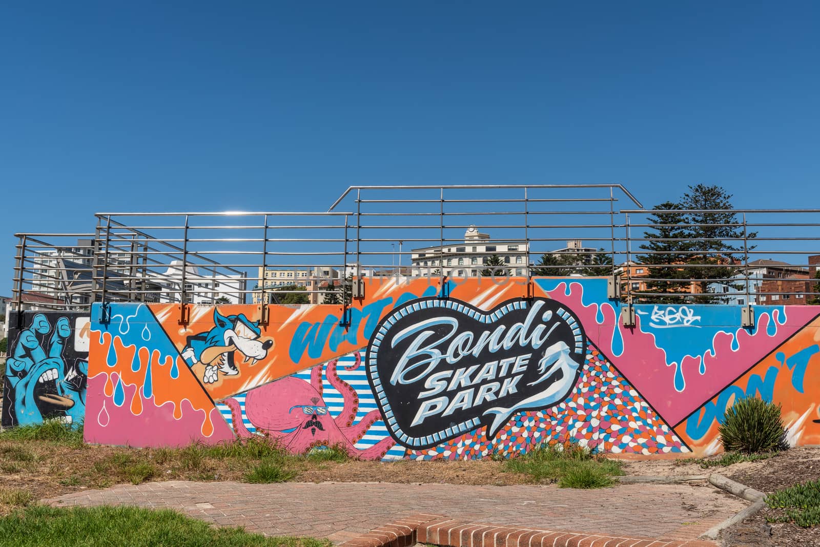 Sydney, Australia - February 11, 2019: Bondi Skate Park with colorfully painted front wall along Bondi Beach under blue sky. Green vegetation in front.