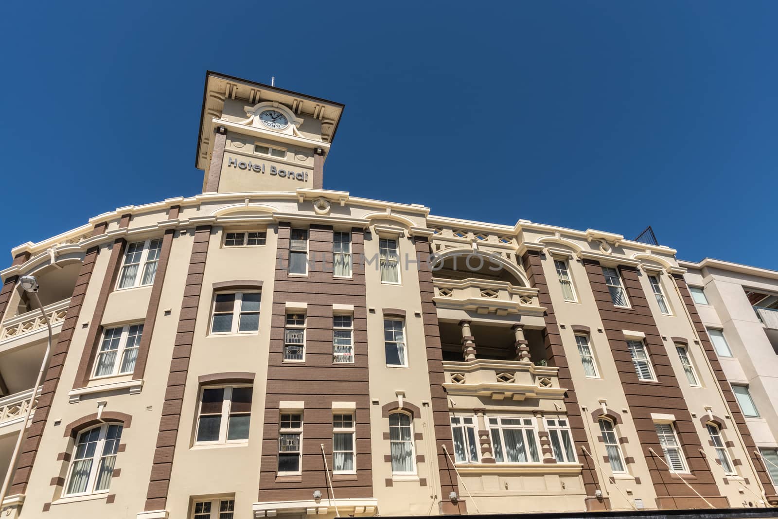 Sydney, Australia - February 11, 2019: Yellow and brown Bondi Hotel facade and clock tower under blue sky in Bondi Beach.