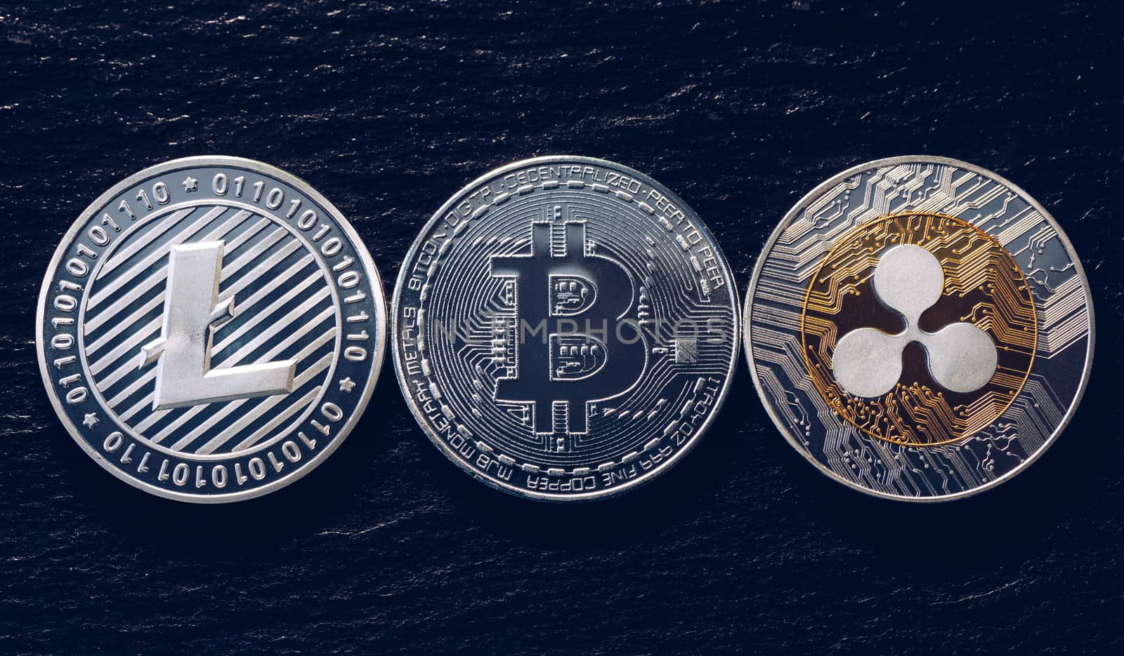 Bitcoin, litecoin and ripple coins currency finance money on graph chart background. Bitcoin as most important cryptocurrency concept. Stack of cryptocurrencies with a golden bitcoin in the middle.