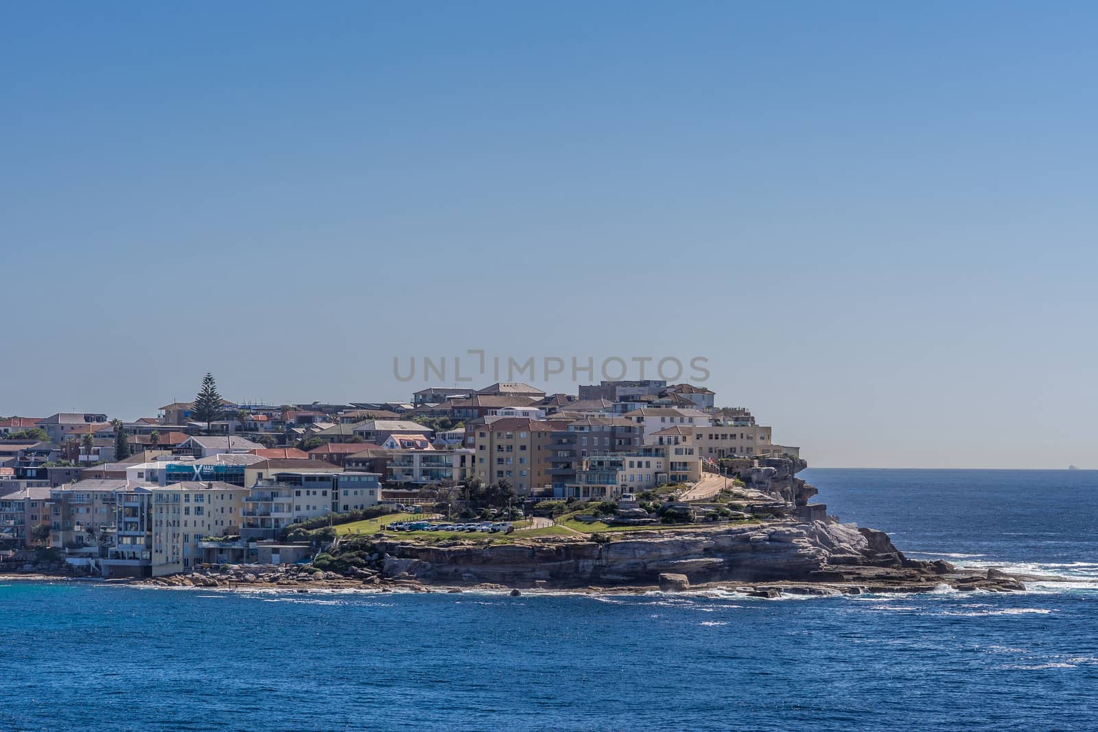 Sydney, Australia - February 11, 2019: Lands end with Sam Fiszman Park and buildings under blue sky and surrounded by blue sea water.