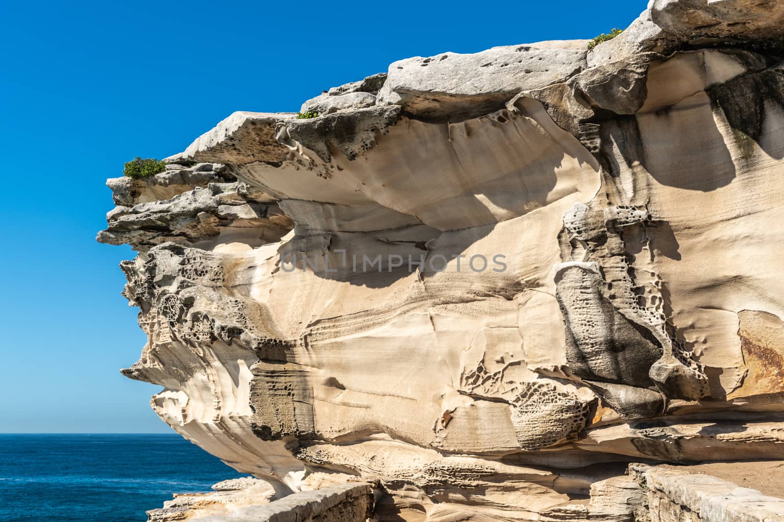 Sydney, Australia - February 11, 2019: Closeup of Mackenzies Point beige rock formation on South shore lands end of Bondi beach. Blue water and blue sky.