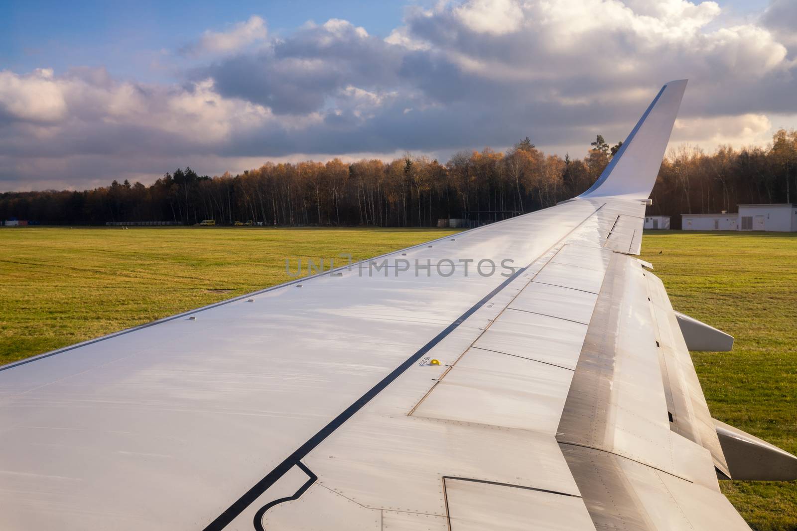 Wing of the plane in the airport. View of plane wing from airplane window. Wing airplane over ground.
