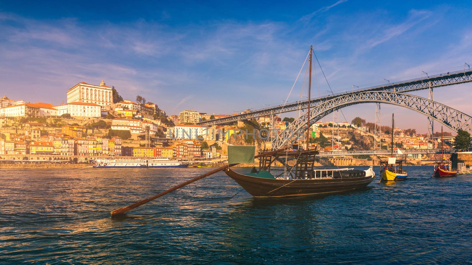 Port wine boats at the waterfront with Dom Luis bridge and the old town on the Douro River in Ribeira in the city centre of Porto in Porugal in Europe. Portugal, Porto