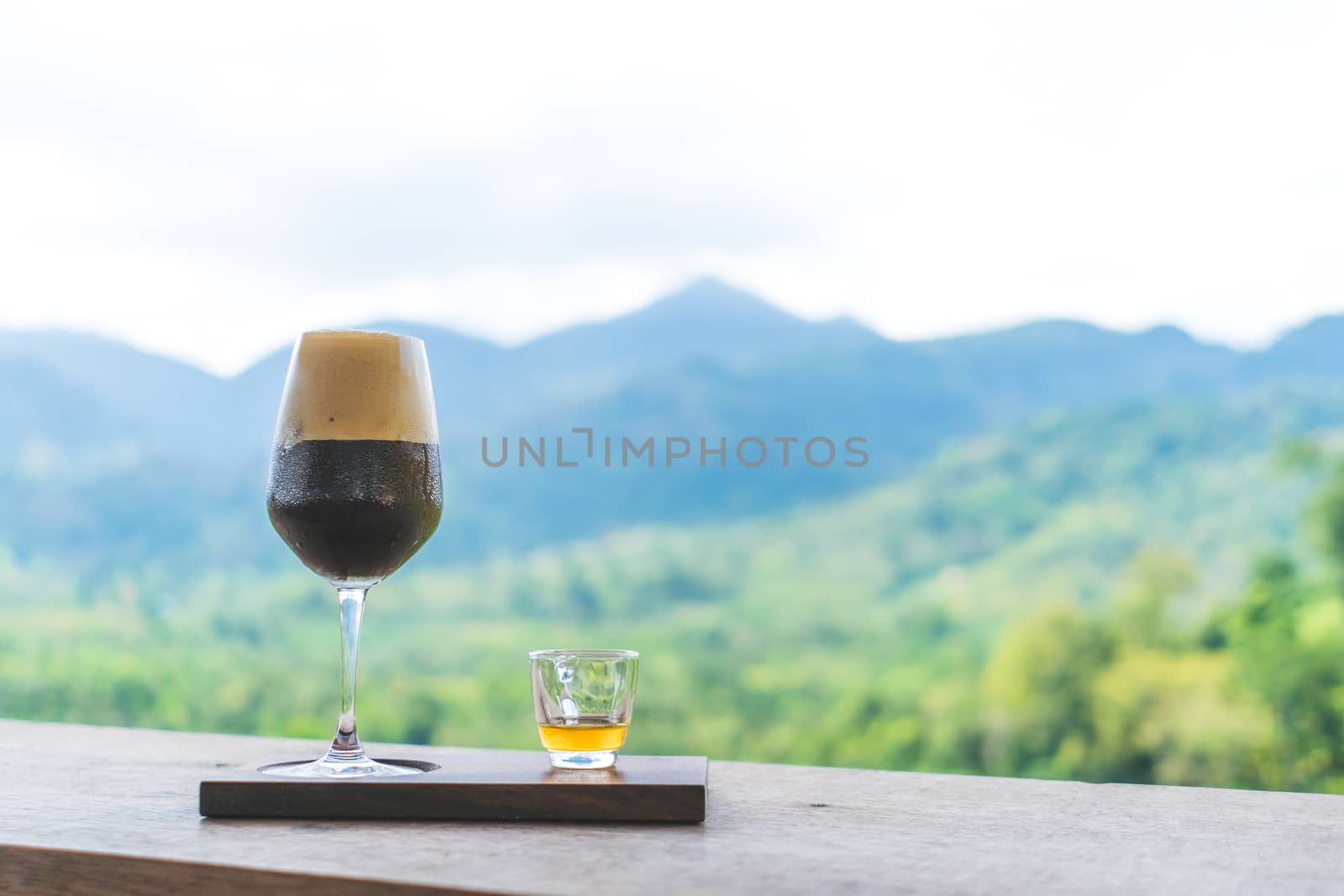 Black coffee or a shot of espresso on wood table with film vintage tone and green nature bokeh  background.