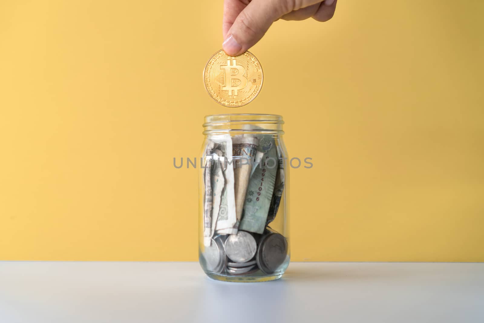 Hand drop gold Bitcoin the jar full of coin and bank notes meaning of saving investment with cryptocurrency digital money fintech online network. Business technology concept.