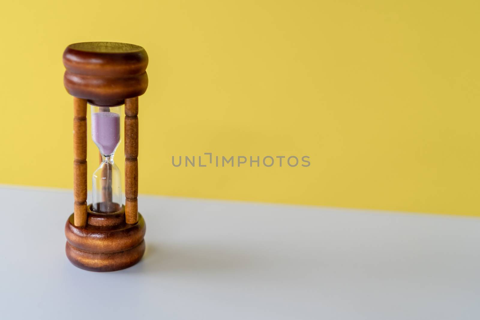 Selective focus of wooden hourglass on yellow background. Time and life concept.