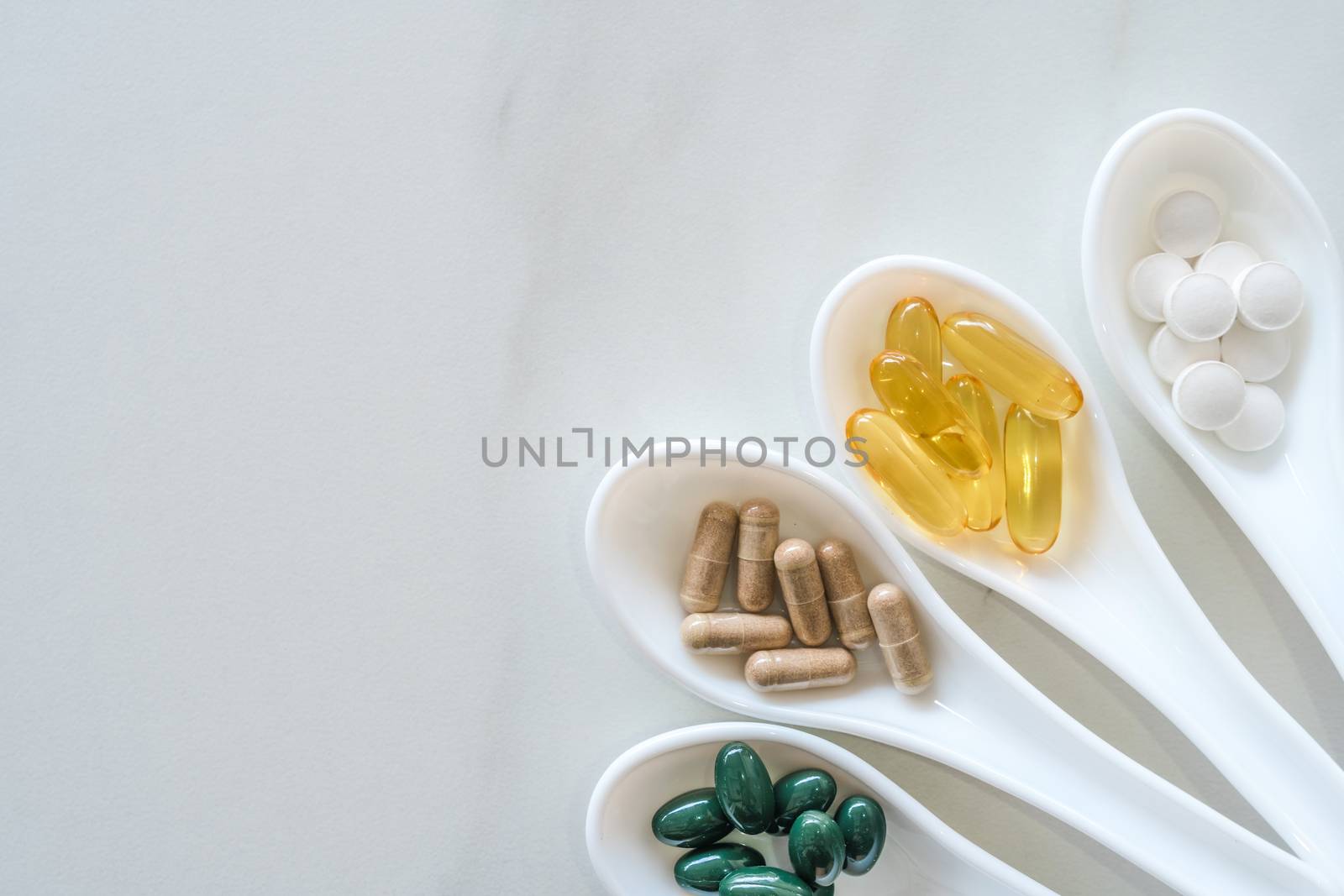 Top view of natural vitamin supplement on white spoon as frame of marble texture background. Healthy eating lifestyle trend concept. by Suwant